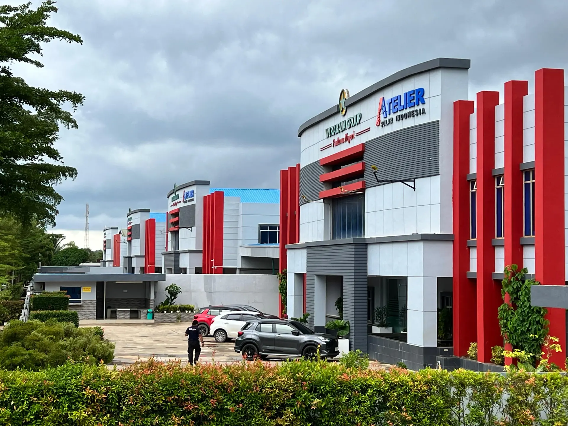 Facade of a building with red accent columns and green landscaping