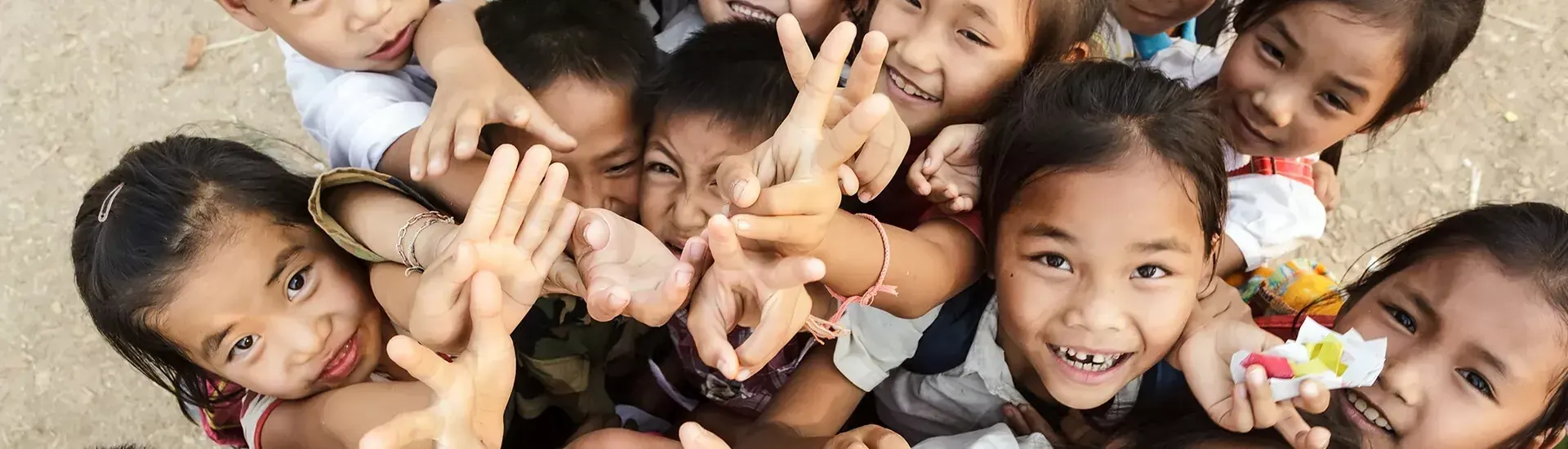 Smiling children making peace signs at the camera